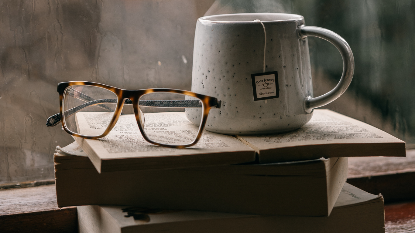 Tee Tasse und Brille auf einem Bücherstapel.